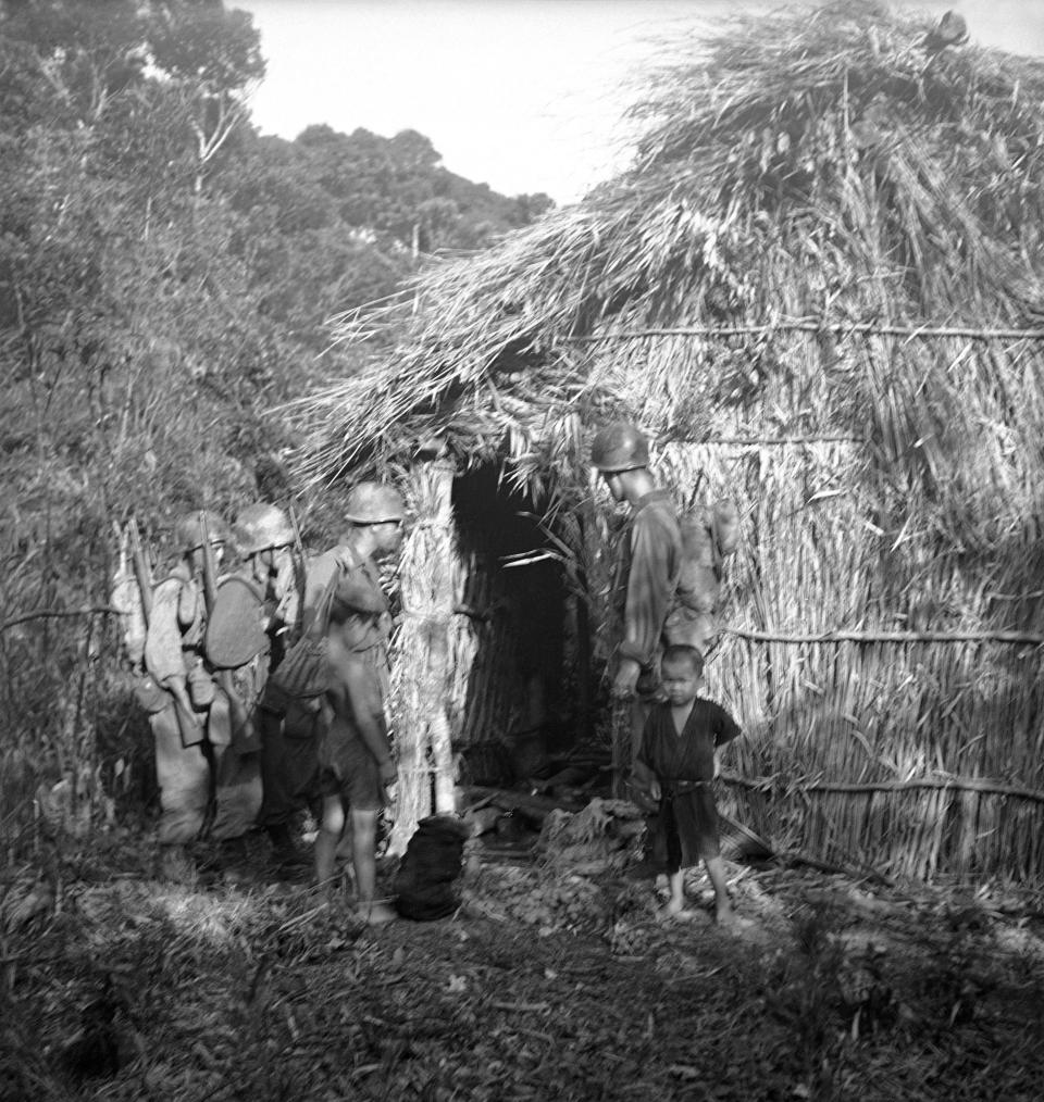 FILE - Troops check a native's hut for hidden Japanese during patrol in northern part of Okinawa, Japan, on July 22, 1945. Okinawa on Sunday, May 15, 2022, marks the 50th anniversary of its return to Japan on May 15, 1972, which ended 27 years of U.S. rule after one of the bloodiest battles of World War II was fought on the southern Japanese island. (AP Photo/Max Desfor, File)