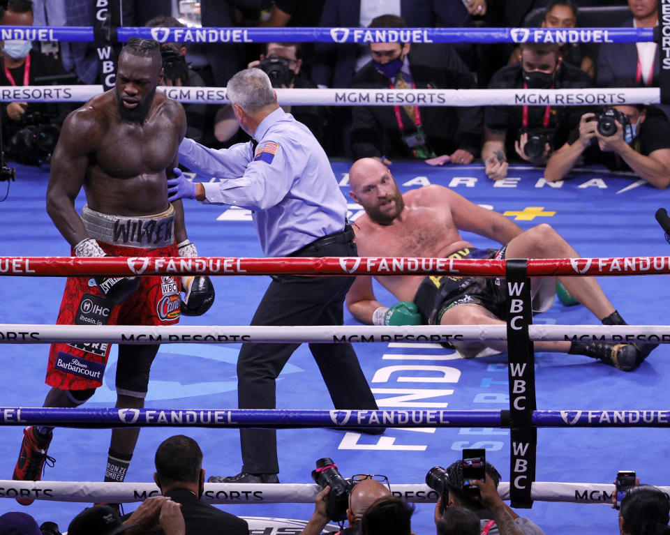 Referee Russell Mora moves Deontay Wilder (pictured left) away from Tyson Fury (pictured right) who is on the floor after a knockdown. 