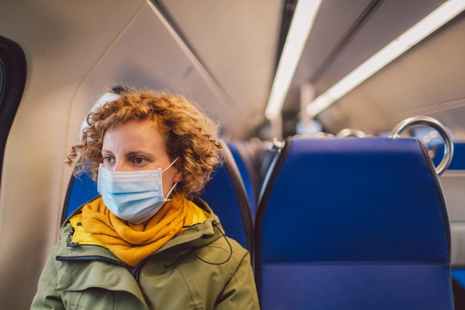 Woman Wearing Mask Sitting In Train - stock photo