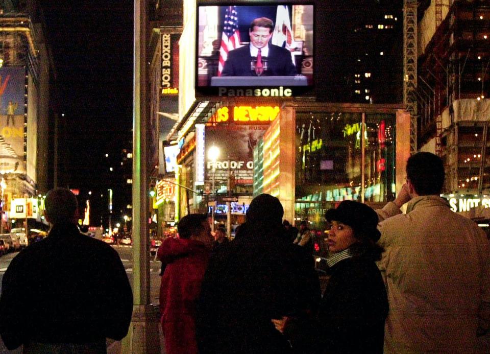 People in Times Square watch Vice President Al Gore concede the race for president to George W. Bush December 13, 2000 on a giant video screen in New York City.