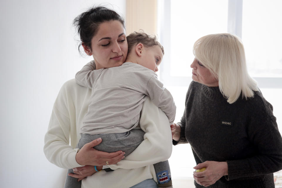 Karina Buiukli, 27-years-old, holds her 2-year-old son, Maxim as her mother Galina Stepanova, right, watches after an interview with The Associated Press, in Brasov, Romania, Wednesday, March 30, 2022. Having escaped from Russian shelling, Ukrainian refugees are now focused on building new lives — temporarily or permanently. Countries neighboring their homeland, like Poland and Romania, are sparing no effort to help them integrate and feel needed in the new environment.(AP Photo/Stephen McGrath)