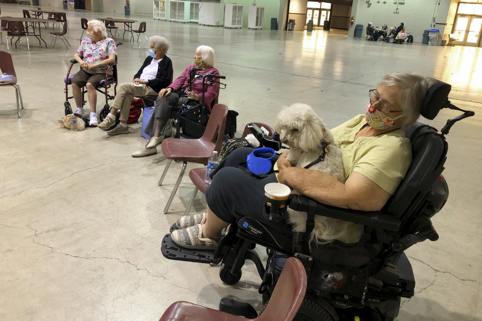 FILE - In this Sept. 8, 2020, file photo Patricia Fouts, 73, sits with her dog Murphy and other evacuated residents of a senior living home in an evacuation center at the Oregon State Fairgrounds in Salem, Ore. More than half a million people have been forced to flee their homes as destructive wildfires sweep across the western U.S., and experts say that could lead to historic numbers of people turning to shelters in the region, all in the middle of the coronavirus pandemic. (AP Photo/Andrew Selsky, File)