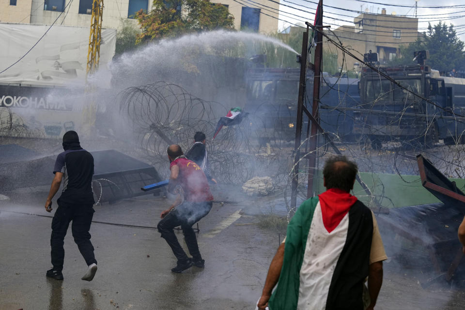 Riot police spray onto protesters with a water cannon during a demonstration, in solidarity with the Palestinian people in Gaza, near the U.S. embassy in Aukar, a northern suburb of Beirut, Lebanon, Wednesday, Oct. 18, 2023. (AP Photo/Bilal Hussein)