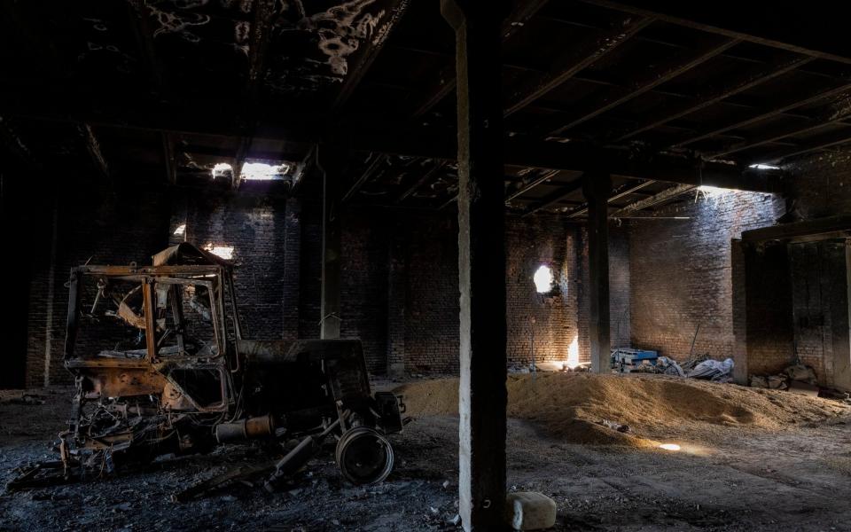 A tractor charred by a Russian attack lies inside a warehouse at a grain farm in Cherkaska Lozova, outskirts of Kharkiv, eastern Ukraine - Bernat Armangue 