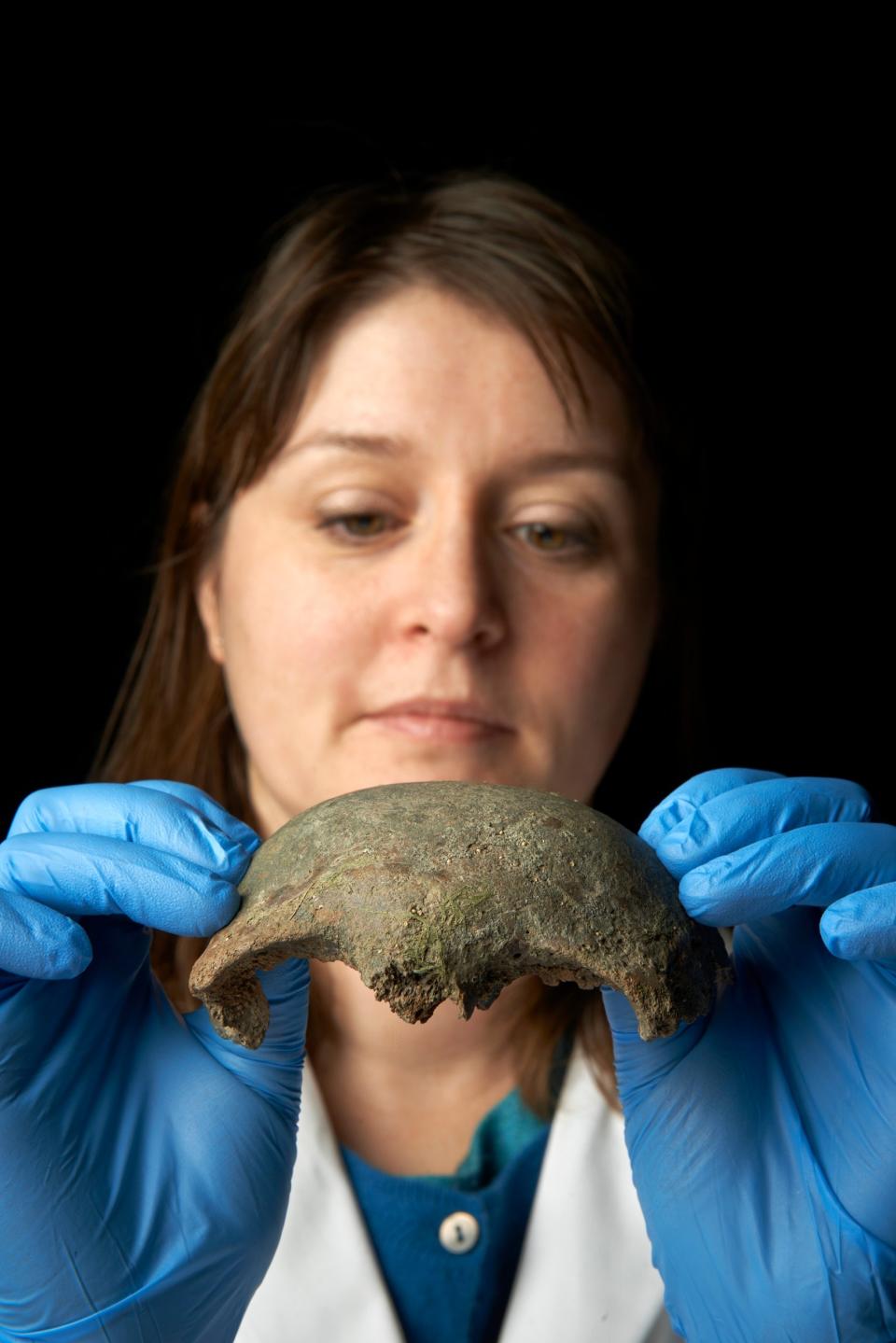 A woman displays the fragment of skull (Museum of London)