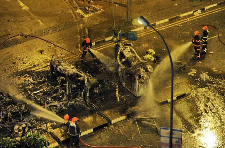 Firemen douse a charred ambulance after a riot broke out in Singapore, in the early hours of December 9, 2013