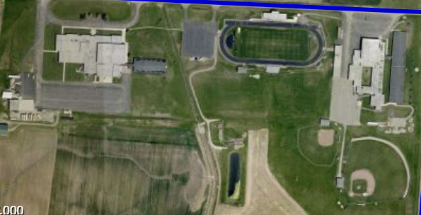 An aerial view of the Madison-Plains Local Schools campus shows (right to left) the current elementary and intermediate schools, football field, and high school.