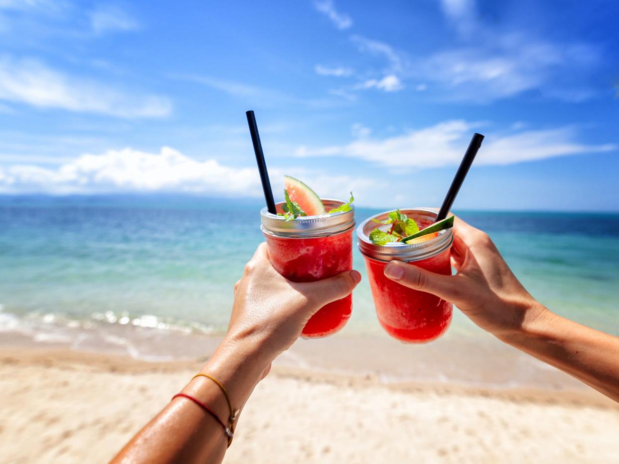 Fresh watermelon juice with a straw in two glasses against a bright tropical landscape, against the background of the sea. Vacation vacations healthy food concept