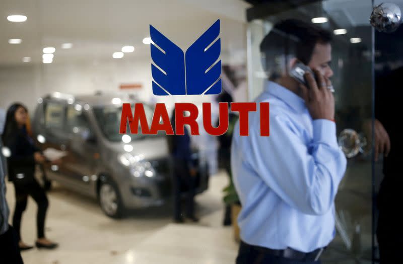 FILE PHOTO: A man speaks on his mobile phone as he exits a glass door with the logo of Maruti Suzuki India Limited at a showroom in New Delhi,