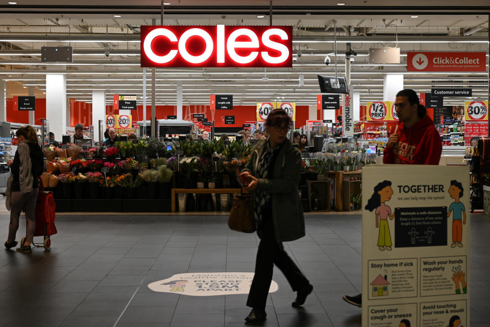 A person walks outside a Coles store. 