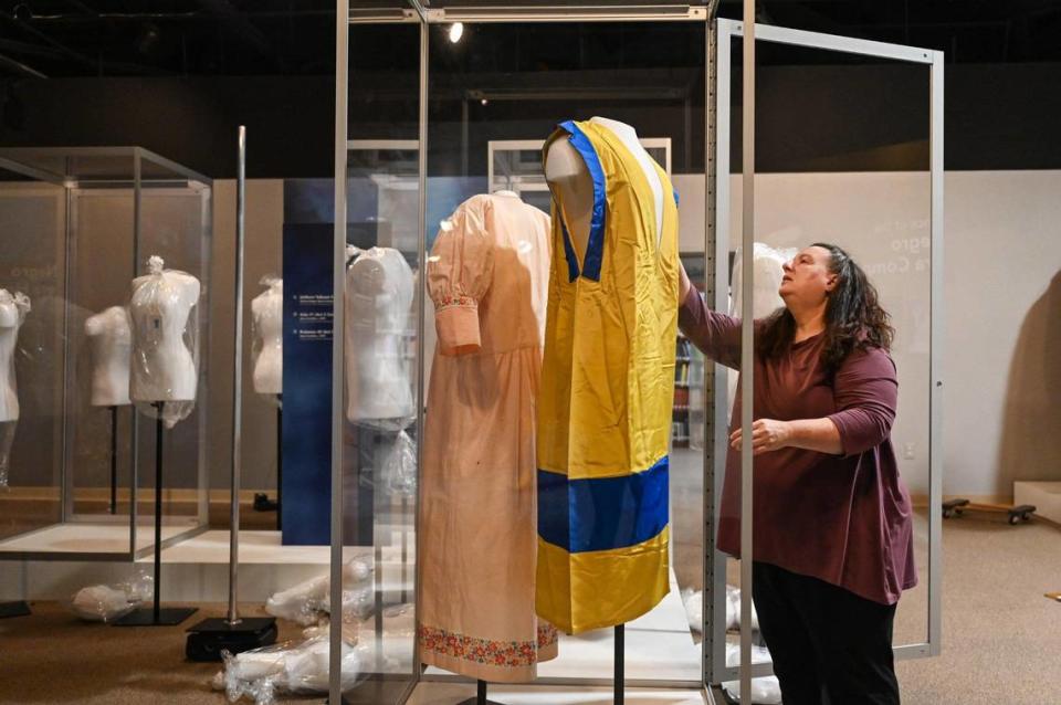 Textile conservator Paige Myers places original costumes into display cases at The Charlotte Museum of History for the “Open Wide the Door” exhibit. This is the first time a museum has staged an exhibit about opera pioneer Mary Cardwell Dawson.