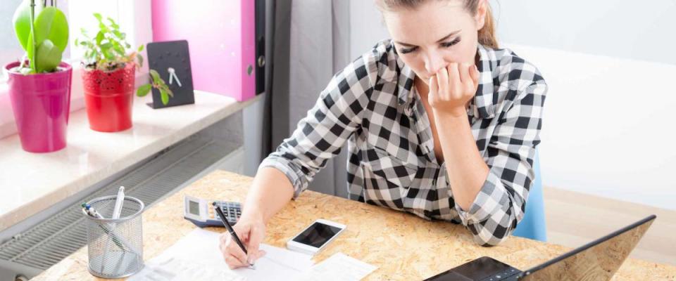 Desperate and worried young woman calculating bills in home office