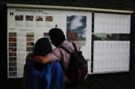 Filmgoers read listings for movies to be screened at the Cineteca Nacional, Mexico's film archive, in Mexico City, Wednesday, Aug. 12, 2020. After being closed for nearly five months amidst the ongoing coronavirus pandemic, movie theaters in the capital reopened Wednesday at 30% capacity. (AP Photo/Rebecca Blackwell)