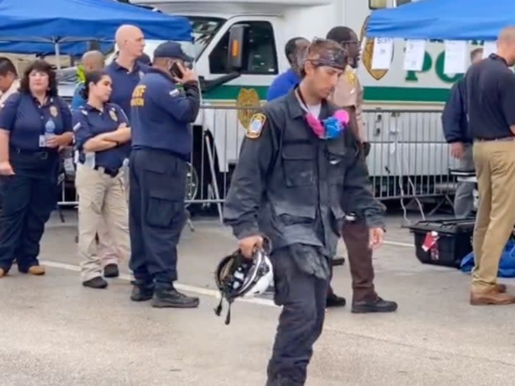 A video posted to TikTok on Wednesday, 30 June, 2021, shows a seemingly exhausted worker walking away from the scene at the partially-collapsed Champlain Towers South condominium in Surfside, Florida. (Pichichipixx/TikTok)