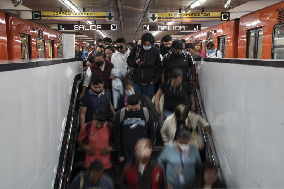 People fill and descend a staircase between subway cars.