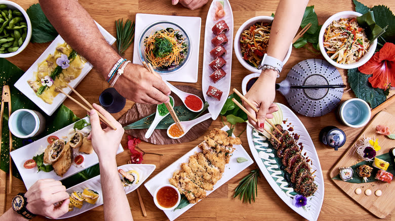 people taking food from Japanese dishes with chopsticks