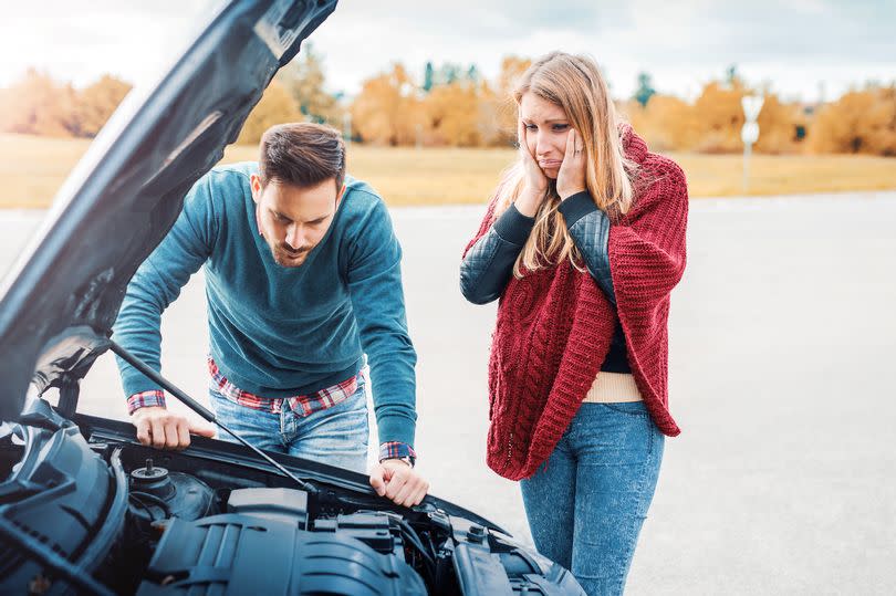 Couple on the road having problem with a car. Broken down car on the road. Traveling and transportation concept