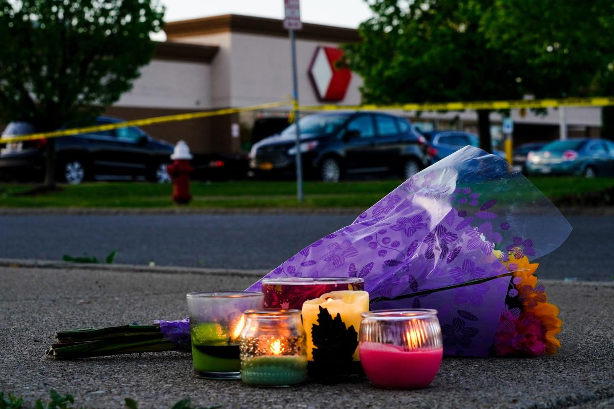 Flowers and candles lay outside the scene of a shooting at a supermarket in Buffalo, N.Y. on Sunday, May 15, 2022.