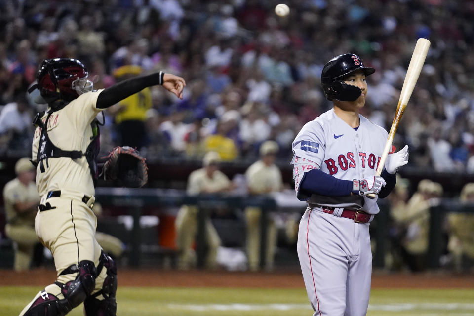 Boston Red Sox's Masataka Yoshida, right, starts to walk away after striking out, while Arizona Diamondbacks catcher Jose Herrera throws the ball to the infield during the third inning of a baseball game Friday, May 26, 2023, in Phoenix. (AP Photo/Ross D. Franklin)