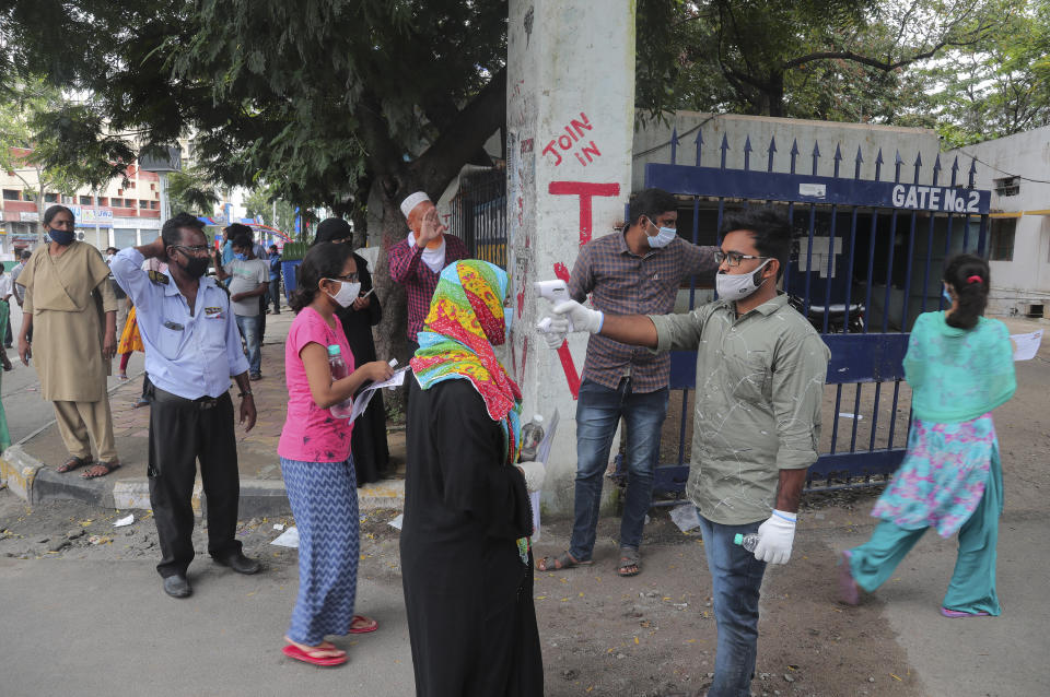 An Indian official wearing a face mask as precaution against the coronavirus checks the body temperature of a candidate before appearing for National Eligibility cum Entrance Test ( NEET) at an exam centre in Hyderabad, India, Sunday, Sept. 13, 2020. NEET is for students who wish to study undergraduate medical and dental courses in government or private medical colleges in India. India's coronavirus cases are now the second-highest in the world and only behind the United States. (AP Photo/Mahesh Kumar A.)