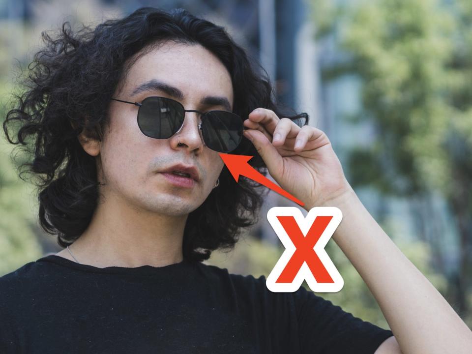 red x and arrow pointing at person wearing black sunglasses