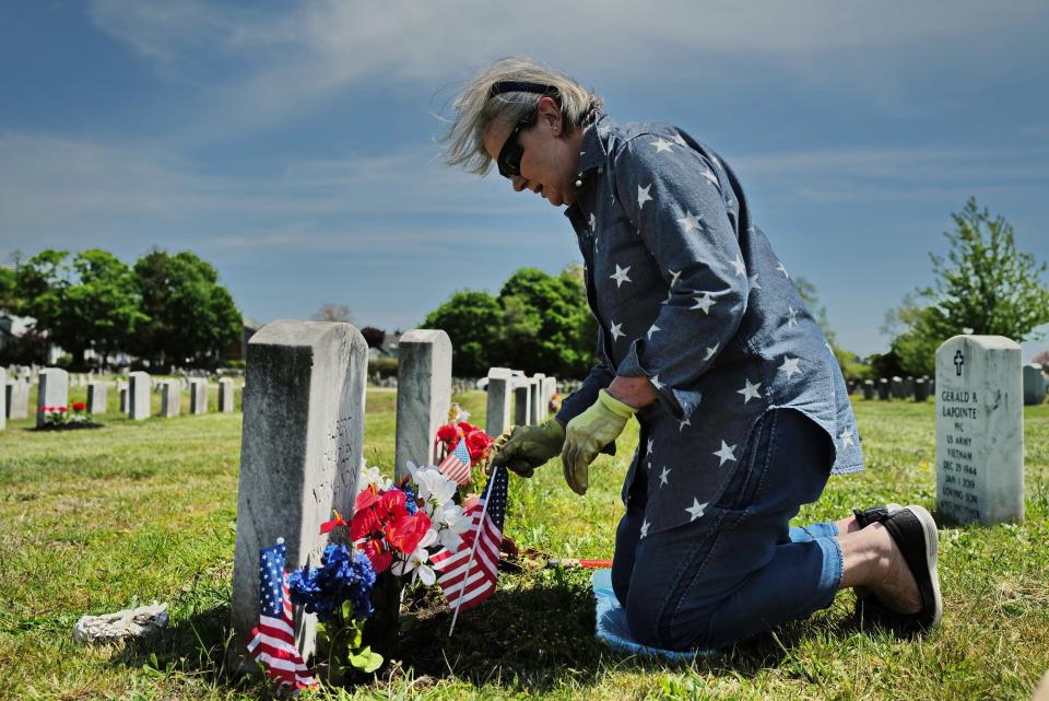 Diane Leclair installs flowers and American flags in front of her father Albert Charles Normandin's grave at Pine Grove Cemetery in New Bedford in preparation for Memorial Day. Mr. Normandin was a Marine during WWII and fought during the battle of Iwo Jima.