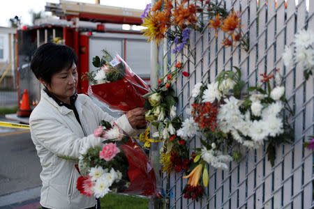 A woman places flowers at a makeshift memorial near the scene of a fire in the Fruitvale district of Oakland, California, U.S. December 3, 2016. REUTERS/Stephen Lam