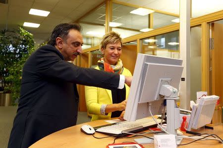 Trainee Wael Samaan, 40, from Syria, gets support from bank employee Sandra Rassmus in a branch of bank 'Sparkasse' in Fuerstenfeldbruck near Munich, Germany, October 20, 2015. REUTERS/Michaela Rehle