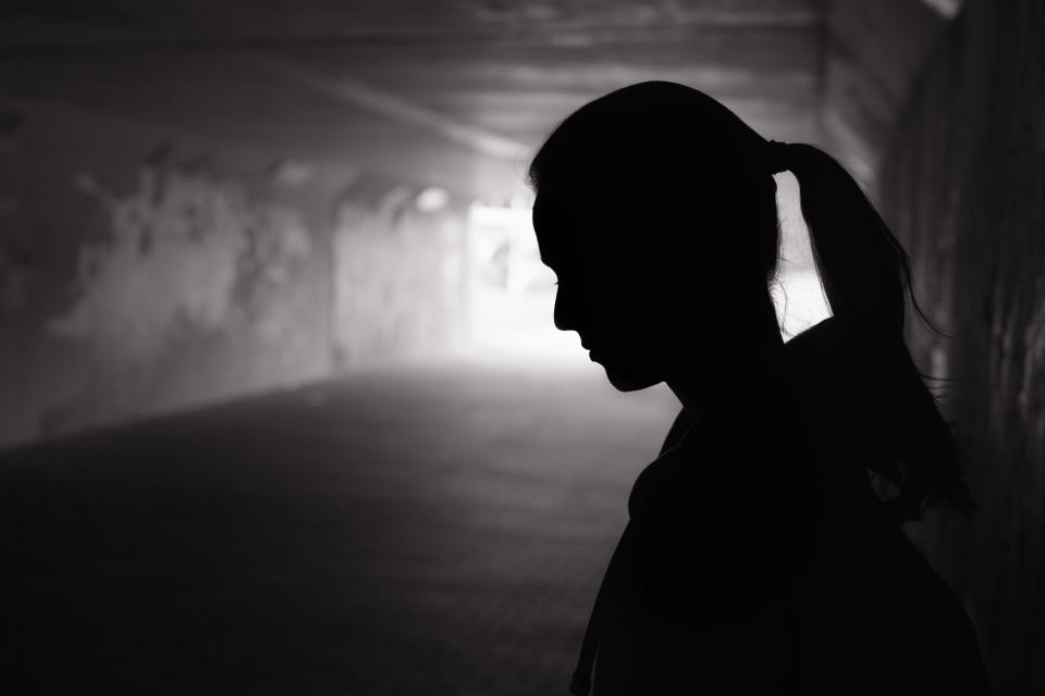 Depressed sad young female standing in a dark tunnel