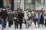 People wearing face masks to protect against the spread of the coronavirus walk on a street in Tokyo Wednesday, March 16, 2022. (AP Photo/Koji Sasahara)
