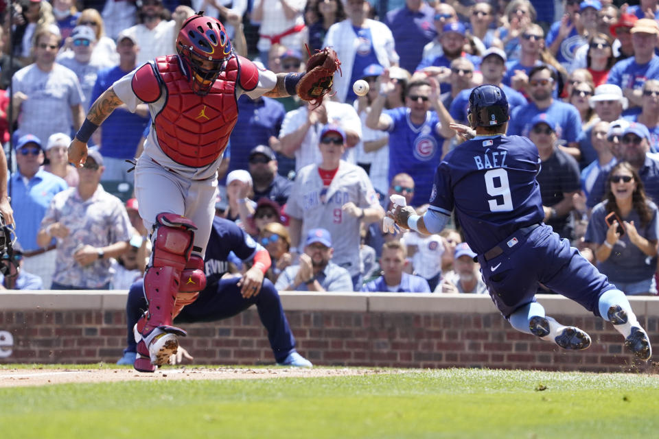 Chicago Cubs'Javier Baez (9) is safe at home plate as St. Louis Cardinals catcher Yadier Molina (4) takes a late throw during the first inning of a baseball game, Friday, July 9, 2021, in Chicago. (AP Photo/David Banks)