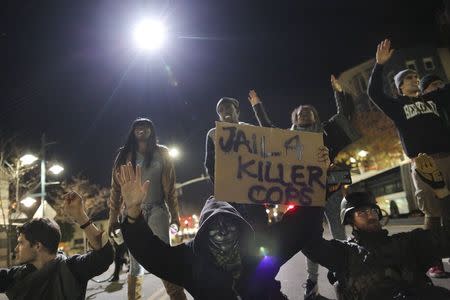 Protesters sit in the street as a police helicopter circles overhead during the second night of demonstrations in Emeryville, California, following the grand jury decision in the shooting of Michael Brown in Ferguson, Missouri, November 26, 2014. REUTERS/Elijah Nouvelage
