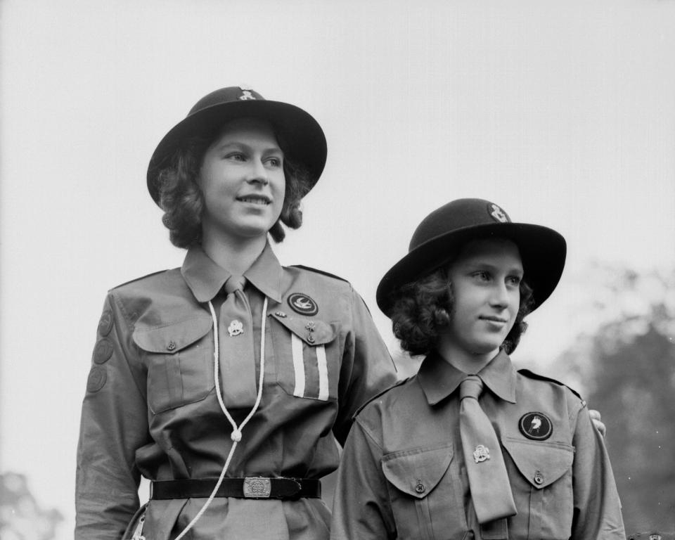 <p>Princesses Elizabeth, left, and Margaret wear Girl Guide uniforms at Frogmore, Windsor, Berkshire, on 30 June 1942. (Getty Images)</p> 
