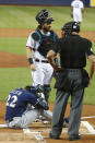 Milwaukee Brewers' Christian Yelich (22) sits on the ground after an injury while at bat as Miami Marlins catcher Jorge Alfaro, rear, and home plate umpire Kerwin Danley look on during the first inning of a baseball game, Tuesday, Sept. 10, 2019, in Miami. (AP Photo/Wilfredo Lee)