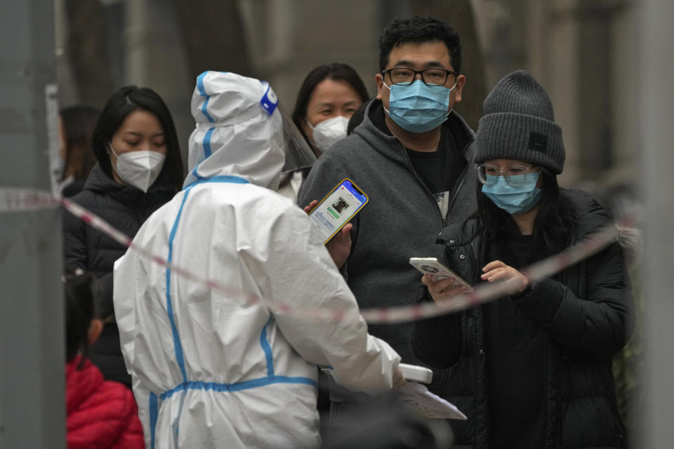 FILE - A man shows his health check QR code as he and others line up to get their routine COVID-19 throat swabs at a coronavirus testing site in Beijing, Thursday, Nov. 24, 2022. (AP Photo/Andy Wong, File)