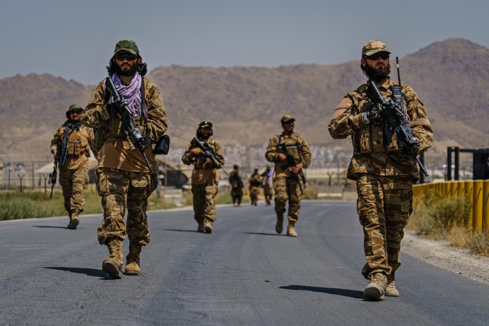 Armed men walk outside the airport.