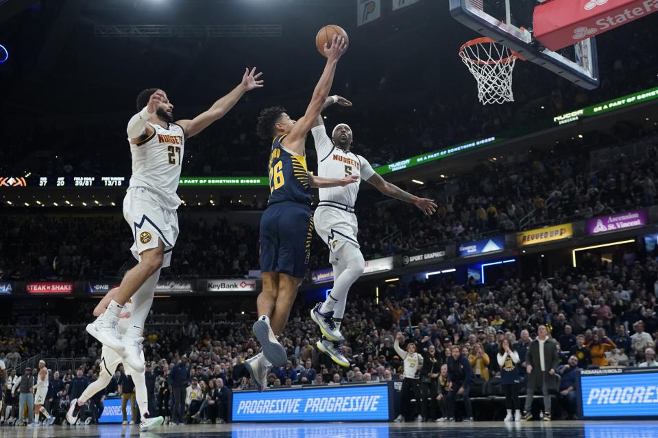 Indiana Pacers' Ben Sheppard (26) puts up a shot against Denver Nuggets' Jamal Murray (27) and Kentavious Caldwell-Pope (5) during the second half of an NBA basketball game, Tuesday, Jan. 23, 2024, in Indianapolis. (AP Photo/Darron Cummings)