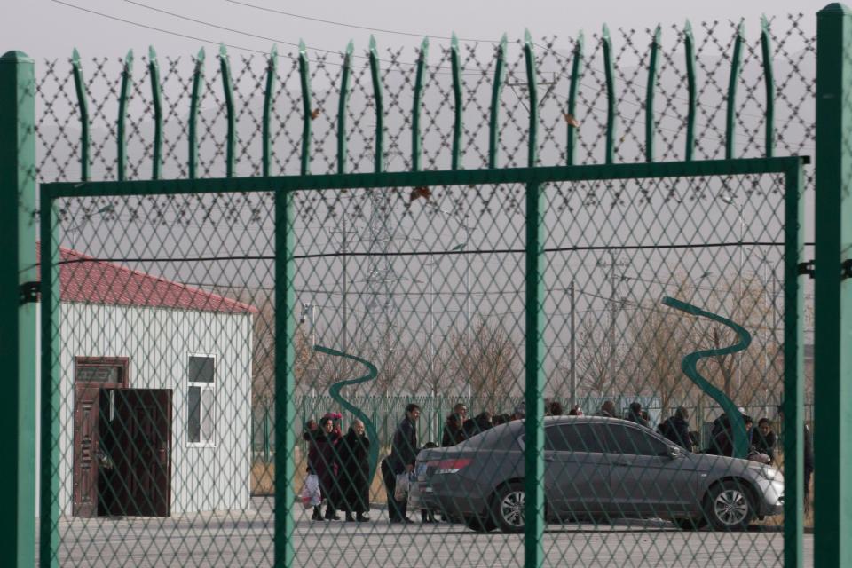 FILE - In this Dec. 3, 2018, file photo, people line up at the Artux City Vocational Skills Education Training Service Center at the Kunshan Industrial Park in Artux in western China's Xinjiang region. Groups representing ethnic minorities in China are again accusing the International Olympic Committee of ignoring widespread human rights abuses as the country prepares to hold the 2022 Winter Olympics in Beijing. Rights groups representing Tibetans, Uighurs, and others have sent an open letter to IOC President Thomas Bach and IOC member Juan Antonio Samaranch, who oversees preparations for the Beijing Games.(AP Photo/Ng Han Guan, File)