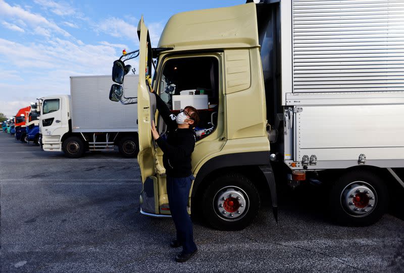 A truck driver Yuichi Tomita takes a break next to his truck during his delivery work at a parking area along the highway in Chiba