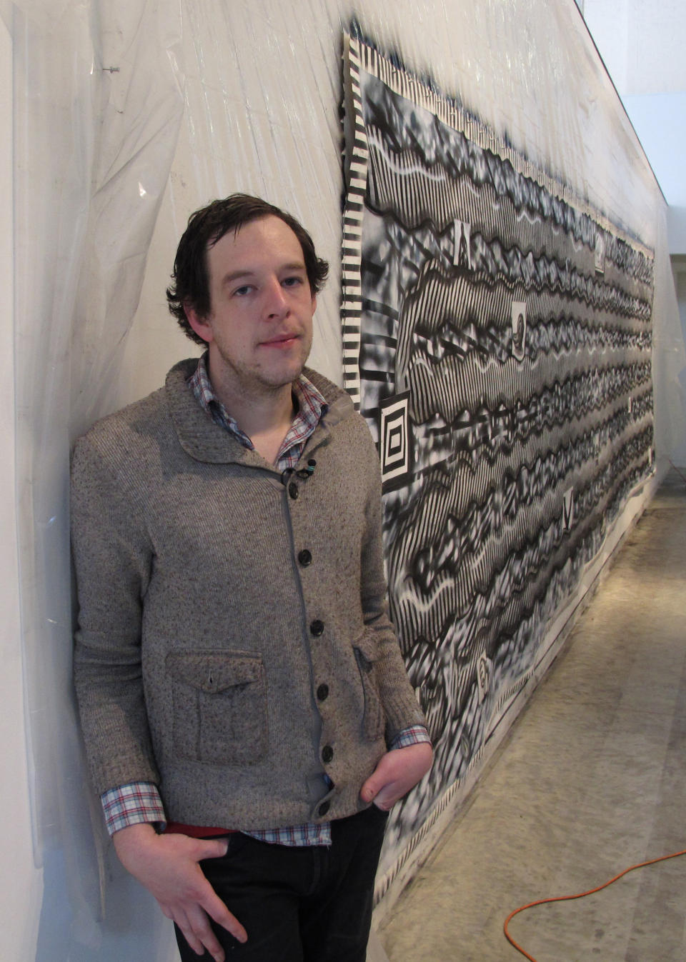 In this Wednesday, Feb. 19, 2013 photo, Ryan Travis Christian stands beside a mural he created over the course of 12 days in the emerging artist gallery at the Contemporary Art Museum in Raleigh, N.C. The Chicago artist completely reworked the wall-sized drawing several days into his first museum exhibition. (AP Photo/Allen Breed)