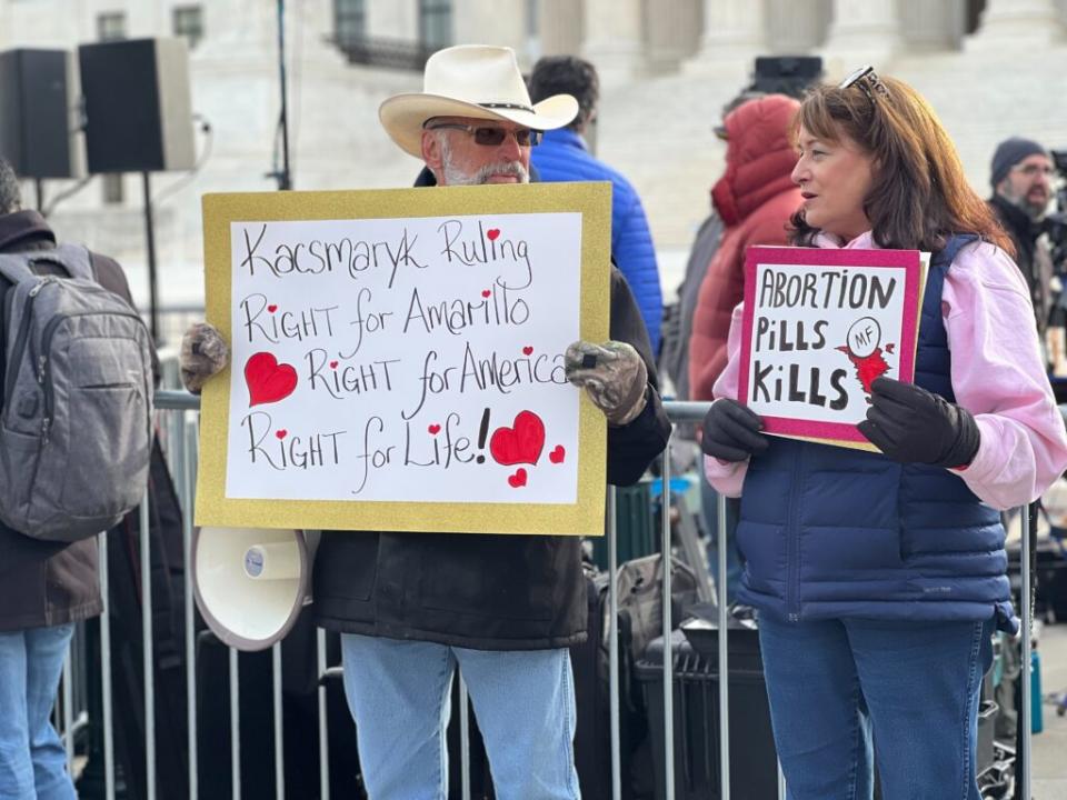 A man holding a sign saying Kacsmaryk ruling right for Amarillo Right for America Right for Life and a woman holding a sign saying ABortion Pills Kills