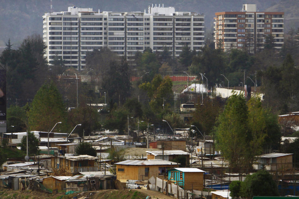 FILE - In this June 18, 2012 file photo, makeshift homes fill the Vila Ermita de San Antonio neighborhood, below, near high-rise apartments located in the Las Condes sector of Santiago, Chile. The efforts of Chile's President Sebastian Pinera to squeeze political advantage from his campaign to reduce poverty have backfired, opening him up to accusations that he distorted statistics to show progress on a campaign promise. (AP Photo/Victor Ruiz Caballero, File)