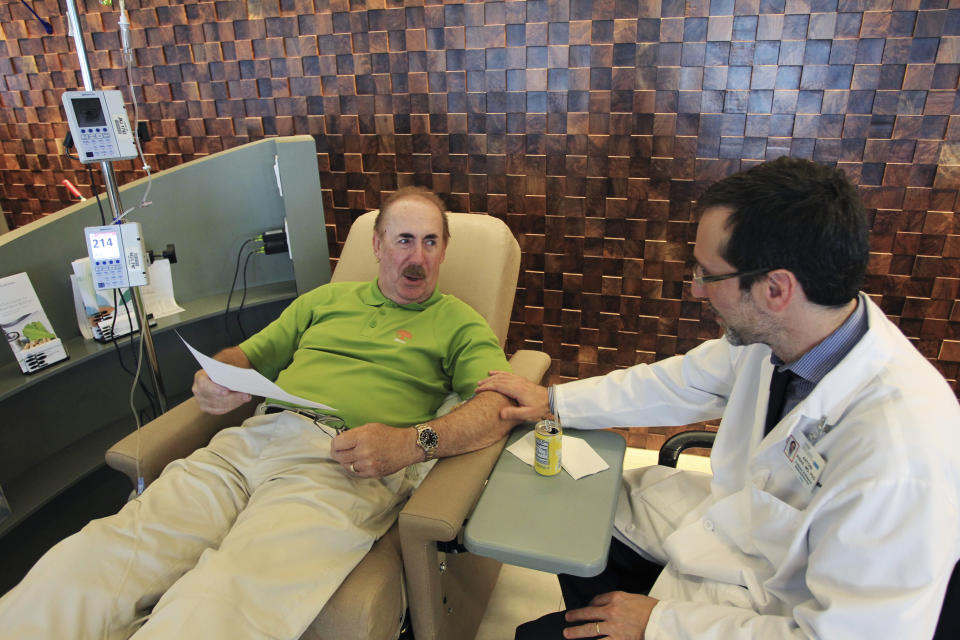 Dr. Antoni Ribas speaks with cancer patient Stew Scannell before Scannell receives an intravenous dose of Lambrolizumab during a promising cancer treatment clinical trial at UCLA Medical Center in Los Angeles, California August 19, 2013. When Scannell was first diagnosed with brain metastases and an incurable melanoma, he was not expected to live long. Now he flies to Los Angeles from his home in Oklahoma every three weeks for injections of the drug Lambrolizumab, or MK-3475, from which he says he feels no negative side effects. He adds that the drug appears to help his body's immune system fight off his cancer cells, and testing indicates a significant reduction in the number and size of his cancers. He is now continuing to work and is helping some of his colleagues rebuild after their losses in the Oklahoma tornadoes earlier this year. REUTERS/David McNew  (UNITED STATES - Tags: HEALTH SOCIETY SCIENCE TECHNOLOGY)