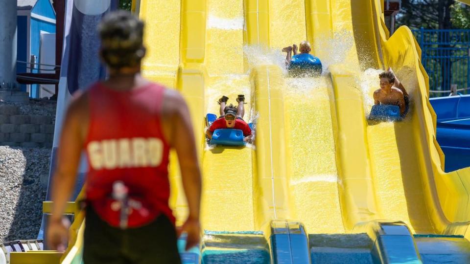 A lifeguard watches as people use a water slide.