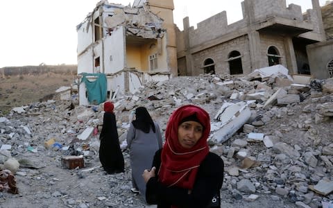 Yemeni women walk through the debris of a housing block allegedly destroyed by Saudi-led airstrikes in Sana a - Credit: YAHYA ARHAB/EPA