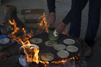 A volunteer member of a community patrol heats breakfast before a trek through the woods looking for illegal logging and avocado planting, on the outskirts of the Indigenous township of Cheran, Michoacan state, Mexico, Thursday, Jan. 20, 2022. Regular citizens have taken the fight against illegal logging into their own hands in the pine-covered mountains of western Mexico. Over the last decade they have seen illegal logging clear the hillsides for plantations of water hungry avocado trees. (AP Photo/Fernando Llano)