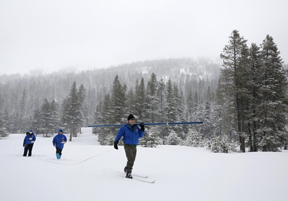 FILE - In this Feb. 28, 2019, file photo, John King, right, of the Department of Water Resources, carries the snowpack measuring tube as he crosses a meadow while conducting the third manual snow survey of the season at the Phillips Station near Echo Summit, Calif. A wet winter likely will fend off mandated water shortages for states in the U.S. West that rely on the Colorado River. But the snow and rain doesn't erase the impact of climate change in a region that's getting drier and hotter. U.S. officials will give a projection Thursday, Aug. 15 for the water supply from a key reservoir serving Arizona, California, Nevada and Mexico. (AP Photo/Rich Pedroncelli, File)