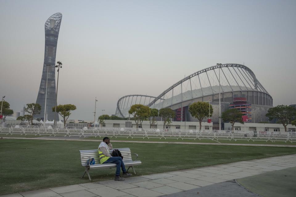 A migrant worker sleeps on a bench before his early morning shift, in front of Khalifa International Stadium, also known as Qatar's national and oldest stadium, which will host matches during FIFA World Cup 2022, in Doha, Qatar, Saturday, Oct. 15, 2022. (AP Photo/Nariman El-Mofty)