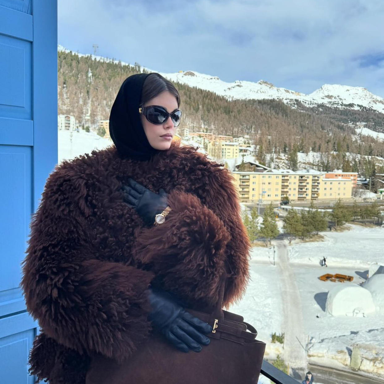  Kaia Gerber wearing a fuzzy brown coat with black leather gloves and black sunglasses. 