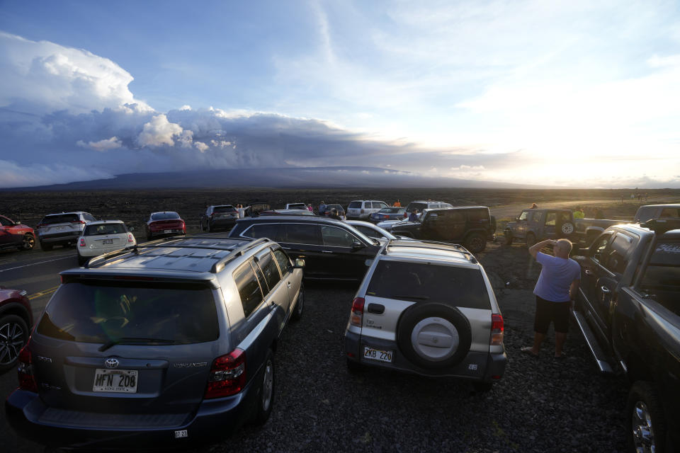 An overflow of cars sit in a parking lot near the Mauna Loa volcano as it erupts Wednesday, Nov. 30, 2022, near Hilo, Hawaii. (AP Photo/Gregory Bull)